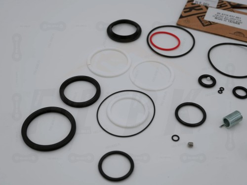 Uszczelki do dampera powietrzengo Rock Shox Deluxe B1, B2 oraz  Deluxe Re:Aktiv A1, B1 na tle etykiety. ZBliżenie na uszczelki kurzowe oraz inne elementy zestawu