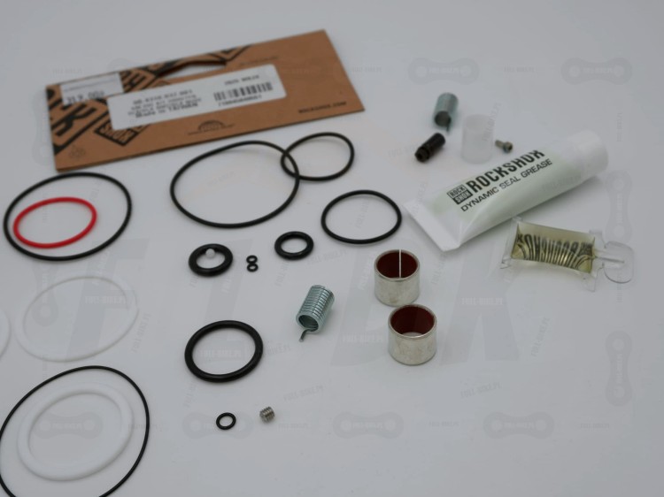 Uszczelki do dampera powietrzengo Rock Shox Deluxe B1, B2 oraz  Deluxe Re:Aktiv A1, B1 na tle etykiety. ZBliżenie na uszczelki kurzowe, olej, smar oraz inne elementy zestawu