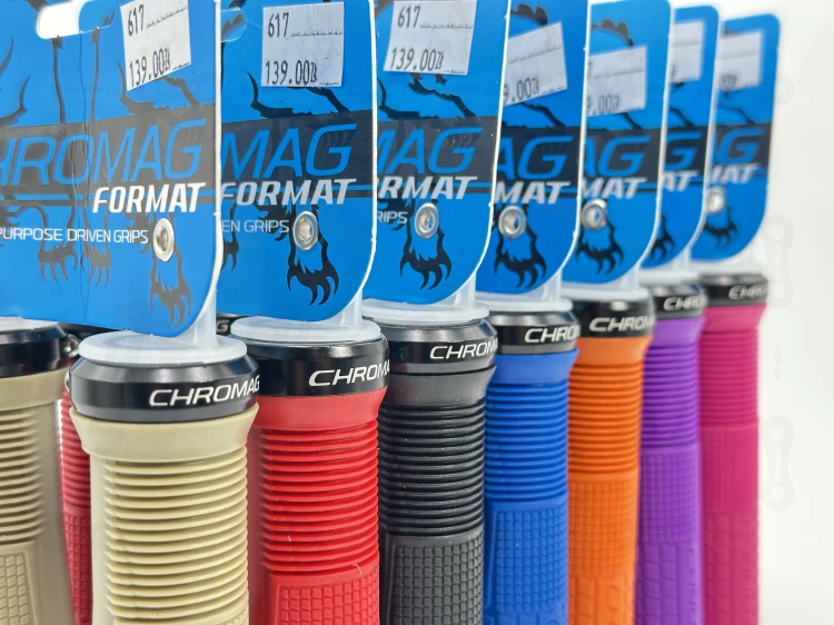 Gripy Chromag Format w kolorze piaskowym pomarańczowym, czarnym, niebieskim, różowym, fioletowym oraz czerwonym. Zbliżenie na obejmę mocującą.