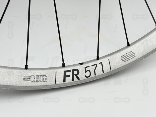 Srebrne koło Dt Swiss FR571 z piastą tanke th490 w rozmiarze 27,5 z czarnymi szprychami dt swiss champion. ZBliżenie na czarny napis FR571