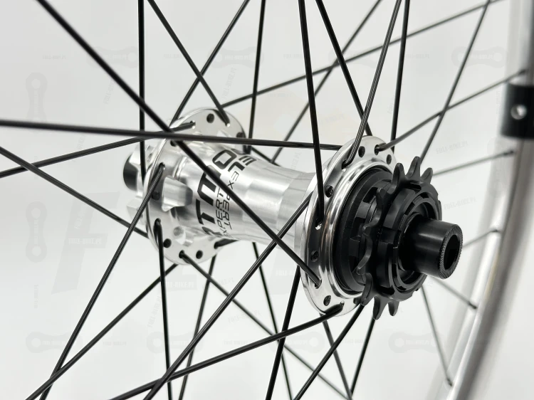 Koło Tylne Reverse Black One 27,5" 148x12 Single speed srebrne z srebrną piastą dartmoor reel expert boost single speed. Zbliżenie na srebrną piastę z czarnym napisem dartmoor oraz bębenek z założoną zębatką.